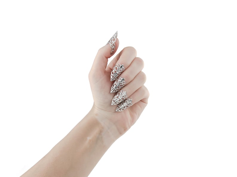 Puede incluir: Una mano con anillos de u&ntilde;as puntiagudos, adornados con plata. Los anillos est&aacute;n decorados con un delicado dise&ntilde;o floral.
