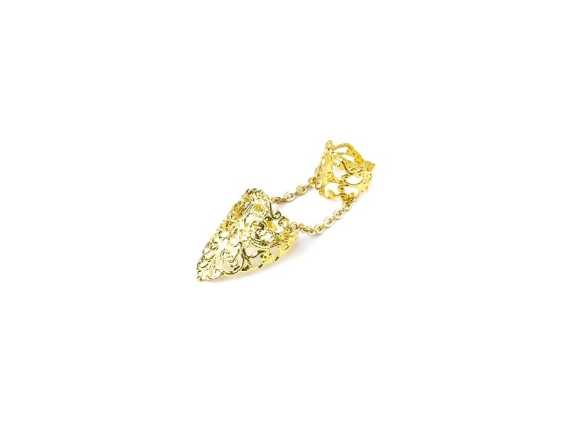 May include: Gold filigree ring with a chain connecting two rings. The ring is designed to be worn on two fingers.