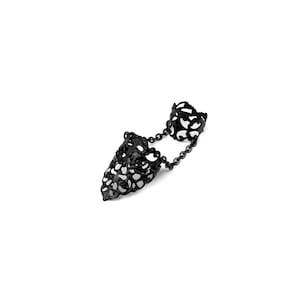 May include: Black filigree double finger ring with a chain connecting the two rings.