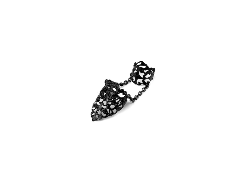 May include: Black filigree double finger ring with a chain connecting the two rings.