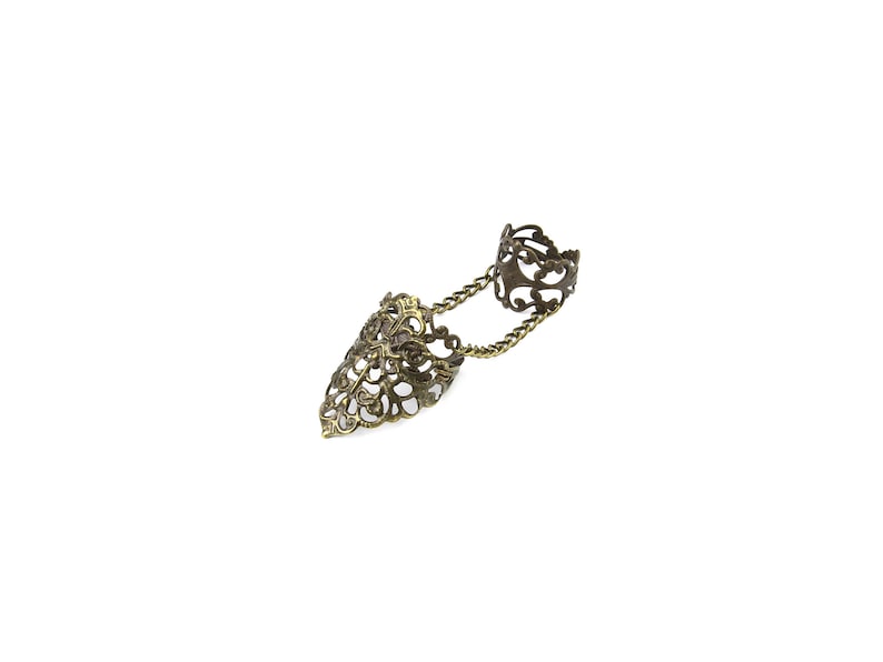May include: A gold-toned filigree ring with a chain connecting to a pointed finger ring.