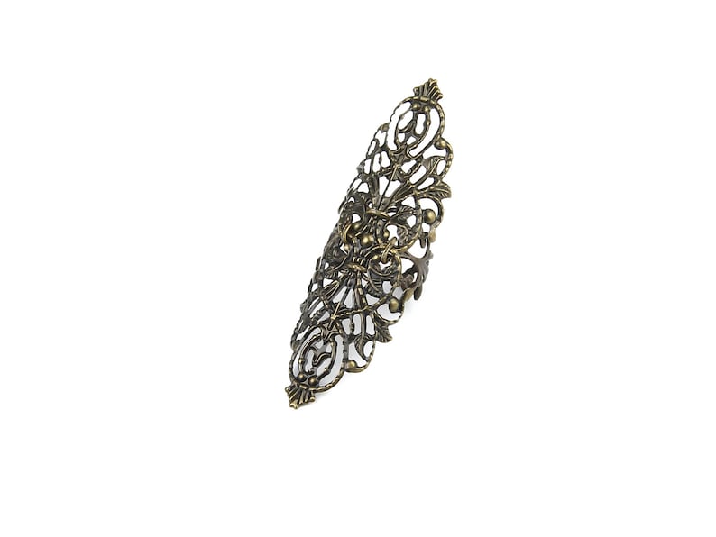 Op de afbeelding: Een grote, sierlijke, goudkleurige ring met een filigraanontwerp. De ring is gemaakt van metaal en heeft een delicaat, ingewikkeld patroon.