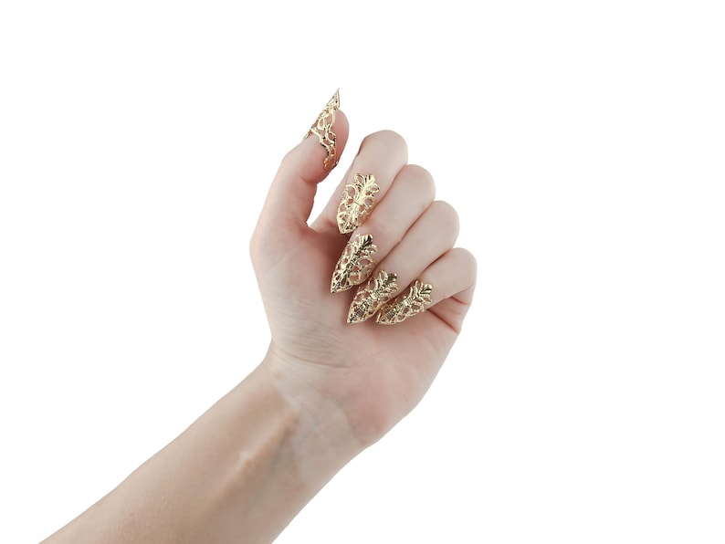 Puede incluir: Una mano con cinco anillos de garra de color dorado con dise&ntilde;os intrincados.