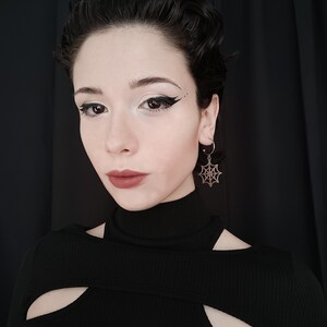 A poised model showcases Myril Jewels' half hoop spiderweb earrings, embodying a dark avant-garde aesthetic. Perfect for gothic and alternative fashion enthusiasts, add a touch of neo-gothic outfit