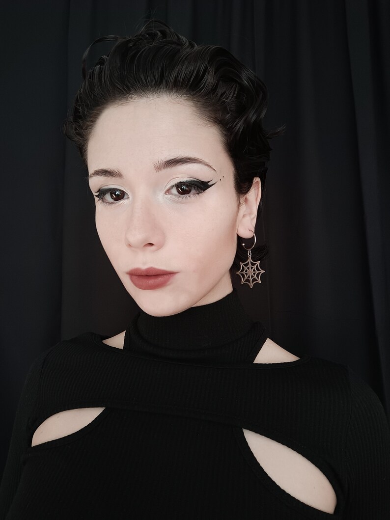 A poised model showcases Myril Jewels' half hoop spiderweb earrings, embodying a dark avant-garde aesthetic. Perfect for gothic and alternative fashion enthusiasts, add a touch of neo-gothic outfit
