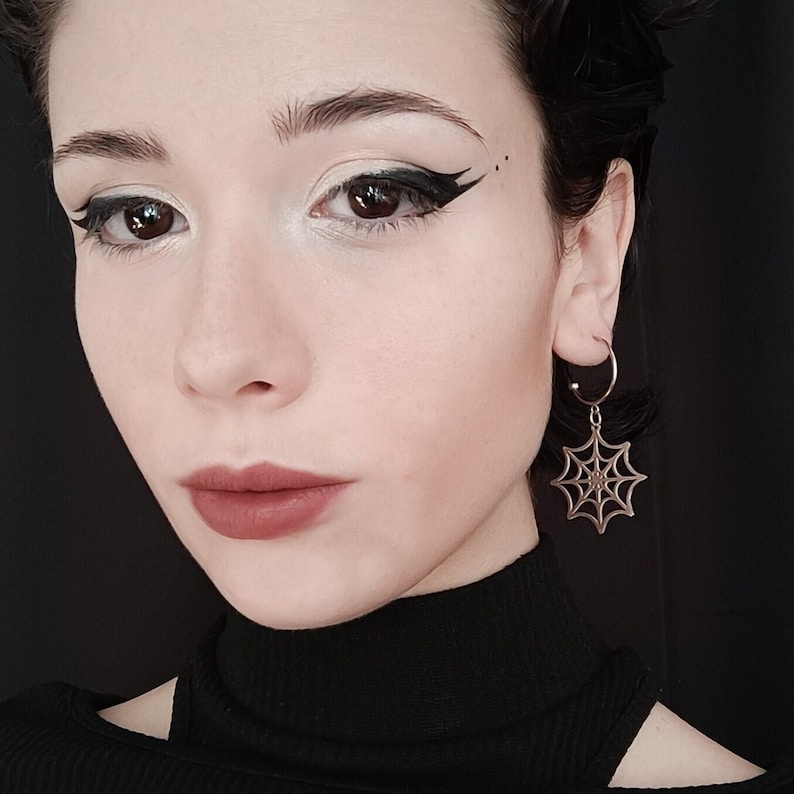 A poised model showcases Myril Jewels' half hoop spiderweb earrings, embodying a dark avant-garde aesthetic. Perfect for gothic and alternative fashion enthusiasts, add a touch of neo-gothic outfit