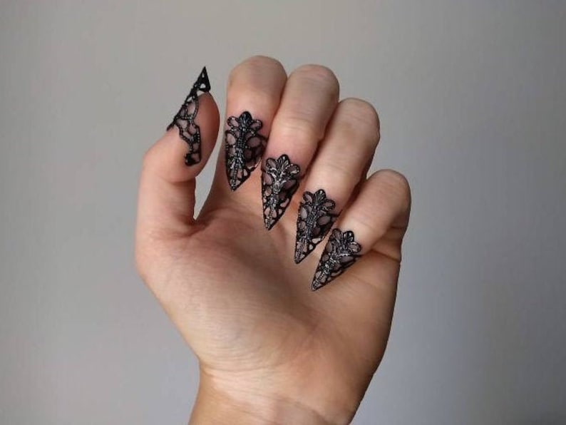 Puede incluir: Anillos de u&ntilde;as de encaje negro con un dise&ntilde;o puntiagudo. Los anillos se llevan en el &iacute;ndice, el coraz&oacute;n, el anular y el me&ntilde;ique.