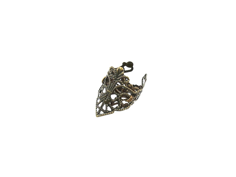 May include: A gold-toned filigree ring with a pointed design. The ring is made of metal and has a delicate, intricate pattern.