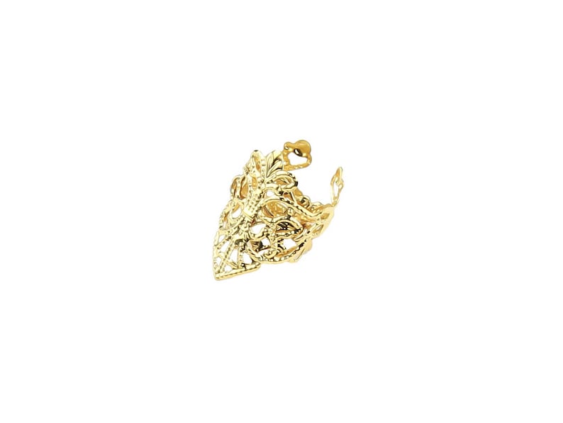 May include: Gold filigree ring with a pointed design. The ring is made of intricate metalwork and has a delicate, ornate look.