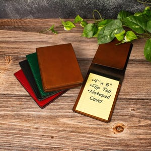May include: A stack of four rectangular leather notepad covers in red, black, green, and brown, with one brown cover open to reveal a yellow lined notepad. The notepad features the printed text: 4" x 6" Flip Top Notepad Cover.