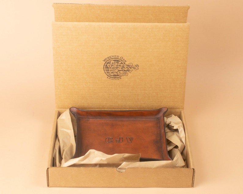 The tray packaged in a simple brown cardboard box, nestled in brown packing paper. The box opens from the top and displays the Wizened Oak Leather logo on the inside of the lid.