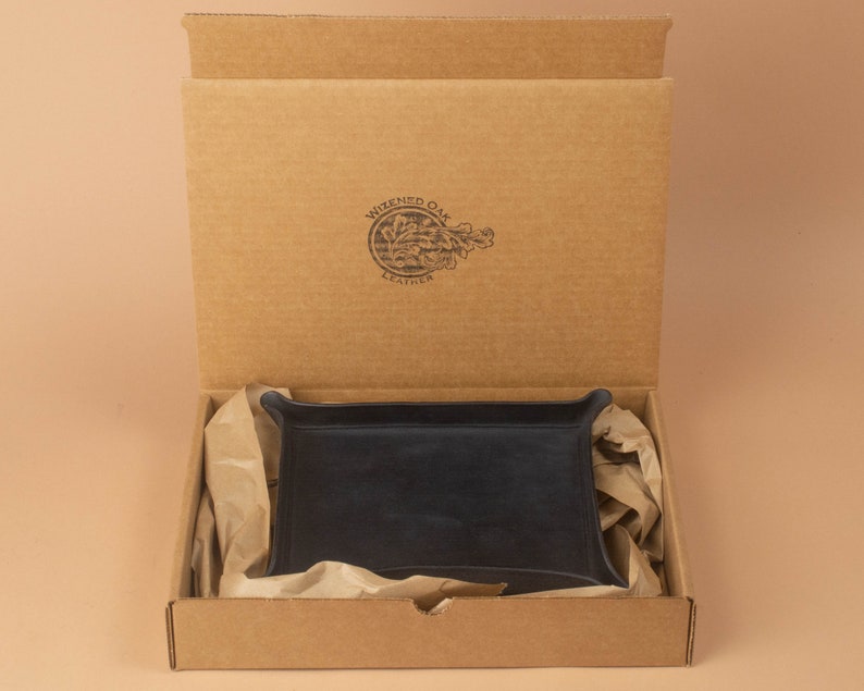 The tray packaged in a simple brown cardboard box, nestled in brown packing paper. The box opens from the top and displays the Wizened Oak Leather logo on the inside of the lid.