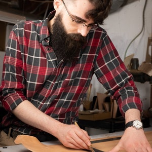 Connor Rademaker, the craftsman, cutting leather for a project in his workshop.