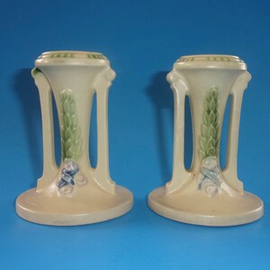 May include: Pair of vintage ceramic candle holders with a cream base, green leaves, and blue and white floral accents.