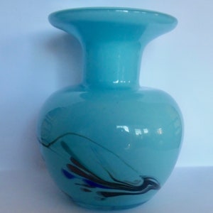 Peut inclure: Un vase en verre bleu clair avec une large ouverture et un motif tourbillonnant de noir, bleu et vert.
