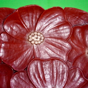 Op de afbeelding: Een decoratief dienblad van bruin leer met een bloemenmotief. Het dienblad heeft meerdere bloemen met witte centra.