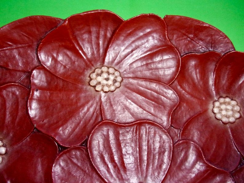 Op de afbeelding: Een decoratief dienblad van bruin leer met een bloemenmotief. Het dienblad heeft meerdere bloemen met witte centra.