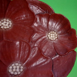 Op de afbeelding: Een decoratief bord met een bruin bloemenontwerp. Het bord heeft drie gestileerde bloemen met witte centra.