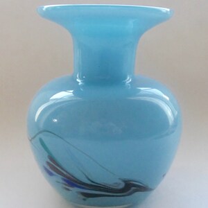 Peut inclure: Un vase en verre bleu clair avec une large ouverture et un motif tourbillonnant noir, bleu et vert.