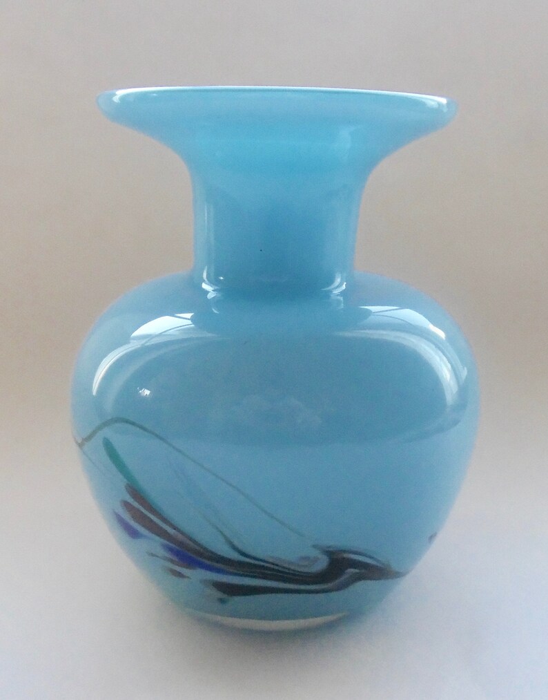 Peut inclure: Un vase en verre bleu clair avec une large ouverture et un motif tourbillonnant noir, bleu et vert.