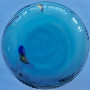 Peut inclure: Un vase rond en verre bleu avec une surface textur&eacute;e et quelques petits motifs de poissons color&eacute;s.