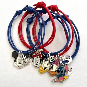 May include: Set of five friendship bracelets with red and blue cords and charms featuring Disney characters Mickey Mouse, Minnie Mouse, Donald Duck, and Stitch. Each charm has an anchor.