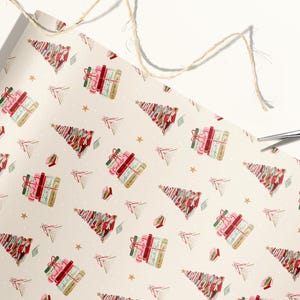 May include: White wrapping paper with a repeating pattern of Christmas trees made of stacked books. The books are red, pink, and green with gold accents. The background is a cream color with small white dots.