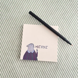 Könnte beinhalten: Eine weiße Karte mit einer Cartoon-Illustration einer Person, die mit dem Text "MERKE" darauf zeigt. Die Karte liegt auf einem grün-weiß gestreiften Hintergrund.