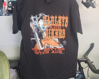 May include: Black t-shirt with an orange graphic of a Harley Davidson motorcycle and the text "Harleys and Bikers Get Better With Age".