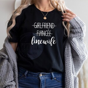 May include: A black t-shirt with white text that reads "Girlfriend - Fiancée - Linewife".
