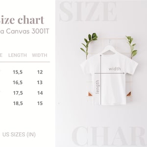 Peut inclure: Un t-shirt blanc sur un cintre, avec un tableau des tailles pour Bella Canvas 3001T. Le tableau affiche les tailles 2T &agrave; 5T, avec des mesures de longueur et de largeur en centim&egrave;tres. Le texte "US SIZES (IN)" est &eacute;galement visible.