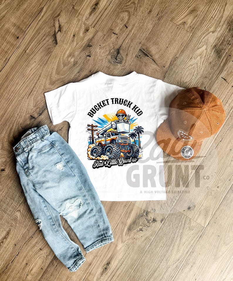 Peut inclure: Un t-shirt blanc avec un dessin de camion nacelle et le texte "BUCKET TRUCK KID". Un jean bleu clair d&eacute;lav&eacute; et une casquette de baseball en velours c&ocirc;tel&eacute; marron sont &eacute;galement pr&eacute;sent&eacute;s. Le t-shirt porte &eacute;galement le texte "Rad Little Grunt co".
