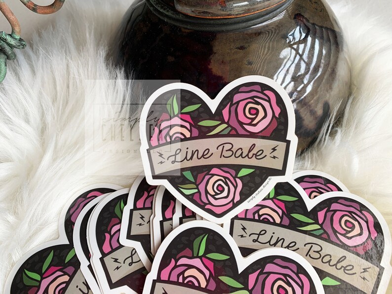 Pu&ograve; includere: Un mucchio di adesivi a forma di cuore con uno sfondo a stampa leopardo bianco e nero. Gli adesivi presentano rose rosa e uno striscione che recita "Line Babe" con fulmini su entrambi i lati.