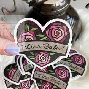 Pu&ograve; includere: Un set di adesivi a forma di cuore con uno sfondo a stampa leopardata bianco e nero. Ogni adesivo presenta una rosa rosa con foglie verdi e uno striscione che dice "Line Babe".