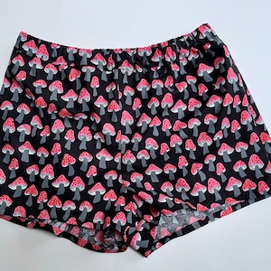 May include: Black shorts with a red and white mushroom print.