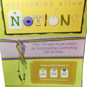 May include: A craft book titled "Designing with Notions" with a yellow and green cover. The cover features the word "Notions" with decorative elements. The book promises over 150 ways to use notions for scrapbooking, cardmaking, and gifts.