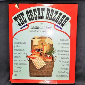May include: The cover of "The Great Bazaar" book by Leslie Linsley. The book features a red border with the title in large, black letters. The cover shows a wicker basket filled with craft items, with text describing the book's contents.