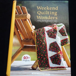 May include: A book titled "Weekend Quilting Wonders" with a small quilt draped over a wooden chair. The quilt has a floral pattern with white star-shaped designs. The book cover has the text "40+ Projects" and is published by "HOUSE of WHITE BIRCHES".
