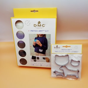 May include: A DIY style felting kit by D.M.C. with the text "PATCH ART KIT". The kit includes a box with felt in shades of white, purple, and brown. Also included are metal animal-shaped cutters for crafting.