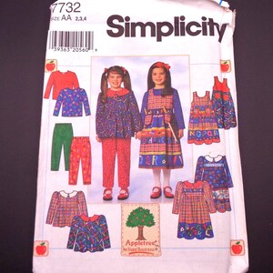 May include: A Simplicity sewing pattern featuring children's clothing designs. The pattern includes options for dresses, tops, and pants in various colors and patterns. The package displays the brand name and the size range.