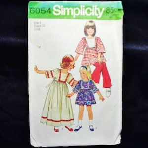 May include: Vintage Simplicity sewing pattern, featuring illustrations of children's clothing designs. The pattern includes a dress, top, and pants. The package is green and white with the number 6054 and the word Simplicity.