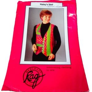 May include: A package for "Haley's Vest" sewing pattern. The package is bright pink with a photo of a woman wearing the vest. The vest is patchwork with red, green, and pink fabrics. The package also has the logo for "Rag" and the text "interesting clothing to sew."
