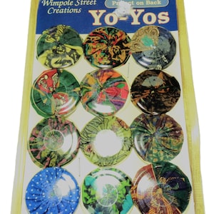 May include: A package of twelve Yo-Yos with various colorful fabric designs. The package has the text "Wimpole Street Creations" and "Yo-Yos" on a blue background. The yo-yos are in a clear plastic blister pack.