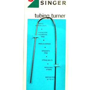 May include: A Singer tubing turner tool on a blue and white card. The tool is a long, thin, silver wire with a hook at one end. The card lists uses for the tool, including making button loops and turning tubing for decorative trim.