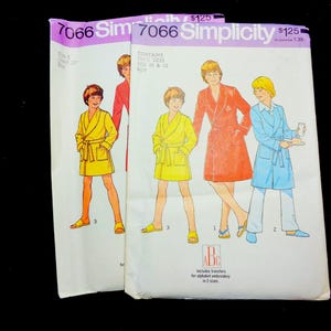 May include: Two vintage Simplicity sewing pattern envelopes. The patterns feature illustrations of people wearing robes. The text on the envelope reads "7066 Simplicity" and "Contains Three Sizes Size 10 & 12 Boy". The price is $1.25.