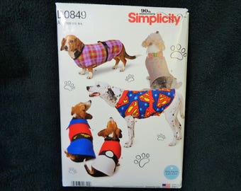May include: Simplicity sewing pattern for dog clothes. The pattern features various dog coats and outfits, including a Superman-themed design and a plaid coat. The pattern includes sizes S-L.