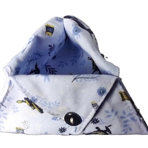 May include: A light blue, triangular fabric pouch with a black button closure. The pouch is patterned with floral and sewing-themed designs in blue, yellow, and black. The interior lining is a lighter blue with similar patterns.