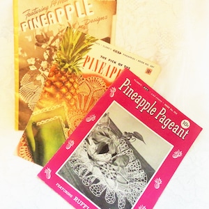 May include: Three vintage crochet pattern booklets with pineapple designs. The covers are in shades of yellow, pink, and white. The booklets feature text such as "Pineapple Designs" and "Pineapple Pageant". A pineapple and doilies are also visible.