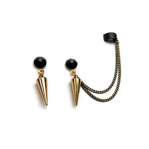 May include: A pair of gold-colored, cone-shaped earrings with black accents. One earring has a black stud and a chain that connects to a black ear cuff. The other earring has a black stud and a cone-shaped pendant.