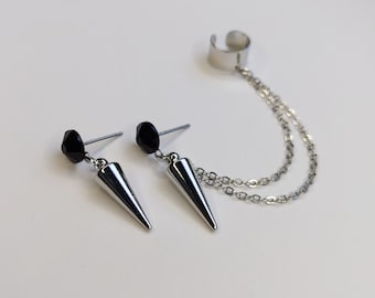May include: A pair of silver-toned earrings with a matching ear cuff. Each earring features a black bead and a cone-shaped pendant. The ear cuff connects to the earrings with two delicate chains.